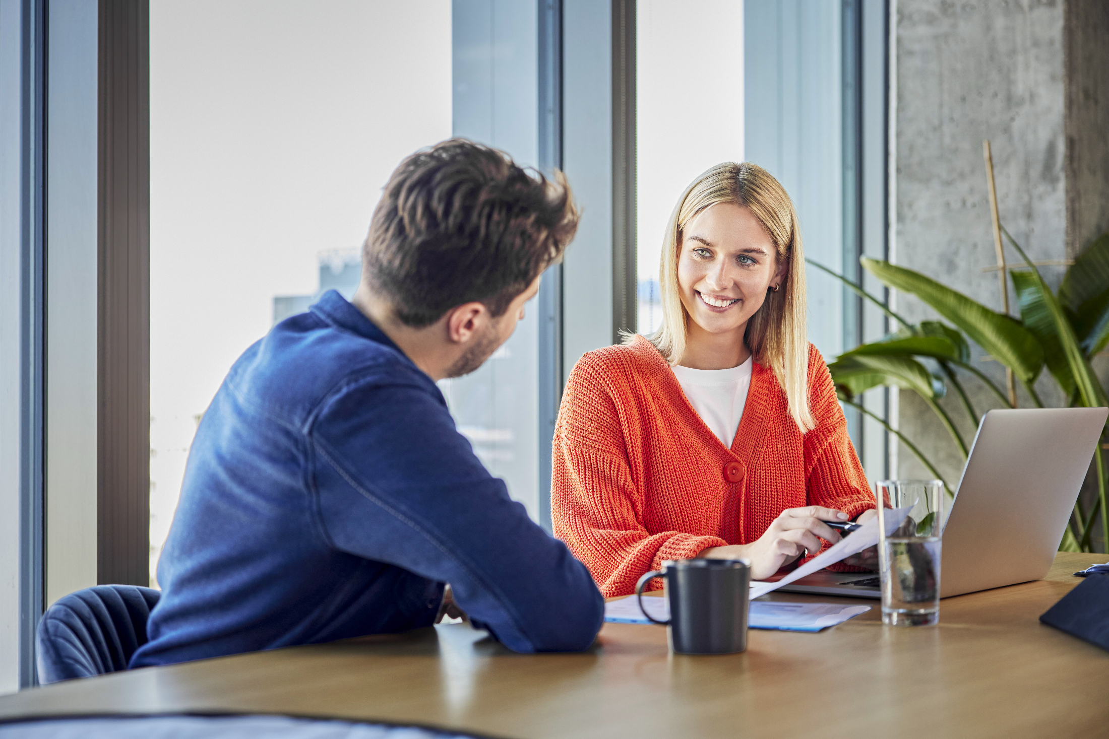 Frau und Mann sitzen an Tisch und besprechen eine Unterlage.